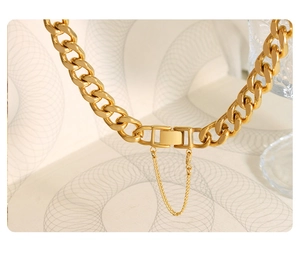 Close-up of golden chunky chain necklace featuring a square buckle and safety chain detail