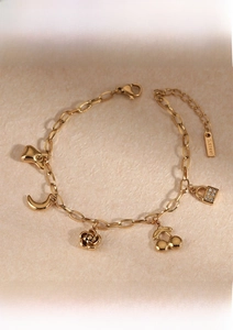 Detail of gold-plated stainless steel charm bracelet with fruit and flower pendants