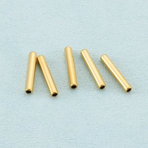 Five gold hollow stainless steel tube beads for DIY jewelry making on blue texture