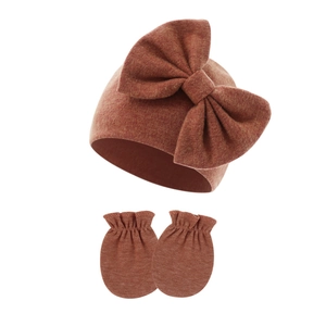 Close-up of caramel knitted baby hat with large bow and matching anti-scratch mittens