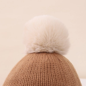 Detalle del pompón de pelo sintético y la textura de punto grueso del gorro de invierno