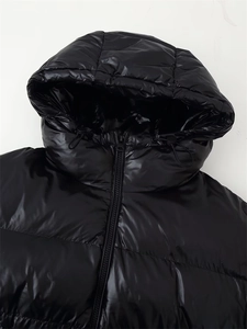 Detail of hooded black shiny puffer jacket featuring adjustable drawstrings and zip closure