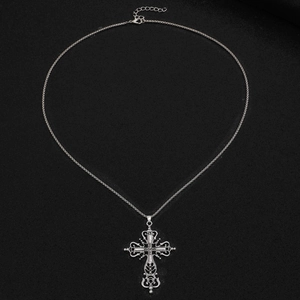 Gros plan détaillé du pendentif croix gothique argenté avec filigranes sur tissu noir