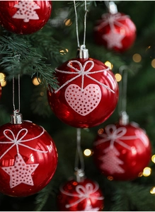 Detail of red Christmas ball ornaments with glitter stars and trees on a festive pine tree