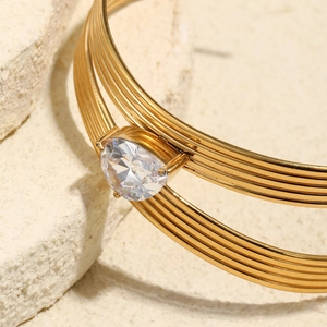Détail du bracelet plaqué or 18K avec zircone en forme de goutte sur fond pierre
