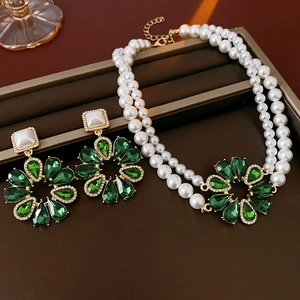 Dettaglio della collana di perle a strati con fiori di cristallo verdi e orecchini