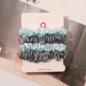 Detail of 4-pack satin scrunchies in light blue and grey on a hanging display card