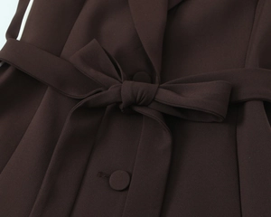 Detail of dark brown vest with a bow tie belt and matching buttons on twill fabric