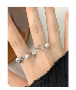 Close-up of S925 silver rings with heart, clover designs and pearls on a hand