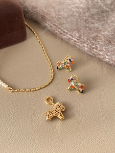 Detail of gold plated pony jewelry set with colorful zircon and pearl on beige leather