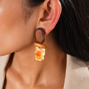 Macro detail of bohemian resin bear earring with wood beads and silver needles