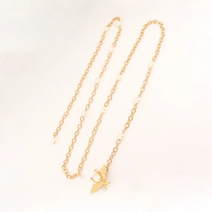 Detail of golden waist chain with white pearls and a delicate bee-shaped pendant charm