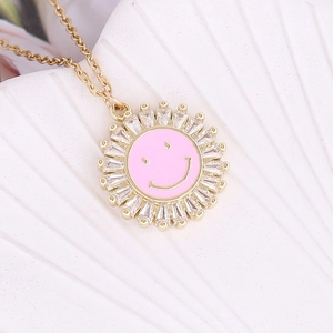 Macro detail of gold sunburst necklace with pink smiley face and cubic zirconia stones