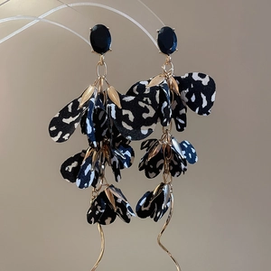Detail view of leopard print fabric flower earrings with long gold chain tassels