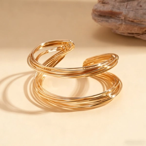 Macro detail of multi-layer golden twisted cuff bracelet with glossy metallic texture