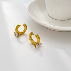 Detail of gold hoop earrings with double cubic zirconia stones on white background