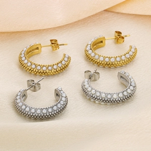 Detail of gold and silver C-shaped stainless steel earrings with inlaid white pearls