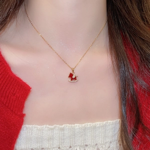 Close-up of a gold-plated necklace featuring a red rocking horse pendant with rhinestones