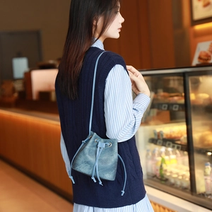 Chic blue drawstring bucket bag with suede texture shown on a crossbody model