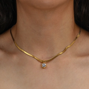 Close-up of elegant gold herringbone chain necklace with round zircon pendant on a model