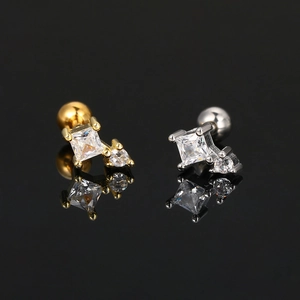 Pair of gold and silver stud earrings with square zircons and screw back on black background