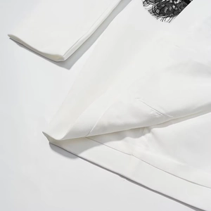 Detail of white dress fabric featuring elegant black lace trim and clean stitching