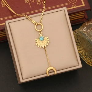 Golden celestial Y-necklace featuring sun, moon, and turquoise elements on a jewelry box