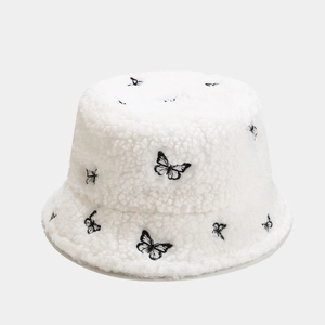 Close-up of white plush teddy fleece bucket hat with black butterfly embroidery details