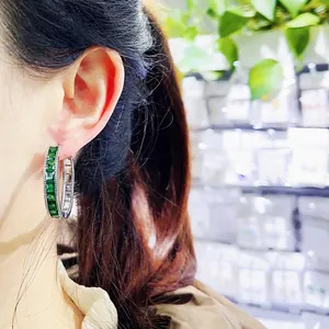 Elegant silver hoop earrings with emerald-cut green gemstones and pave-set diamonds