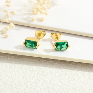 Detail of 18K gold plated earrings with rectangular emerald zircon and white dried flowers