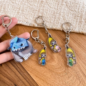 Close-up of four creative acrylic banana cat and shark cat charms for backpacks