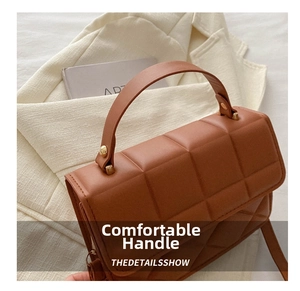 Detail of caramel brown quilted handbag with square pattern and thick handle strap