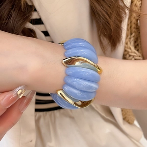 Macro view of wide elastic bracelet with blue textured resin and gold metal modules