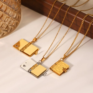 Three openable envelope locket necklaces in gold and silver finish on a rustic tray