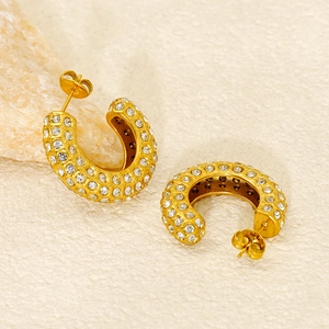 Détail de boucles d'oreilles créoles en C dorées avec pavage de zircons cubiques