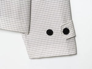 Détail du poignet du trench-coat à carreaux avec boutons et patte de serrage
