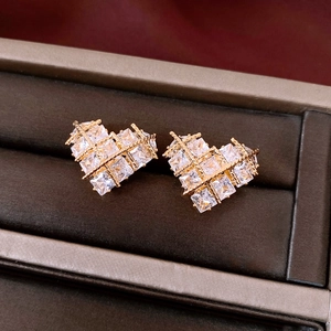 Macro shot of gold-plated heart stud earrings with grid pattern and square cubic zirconia