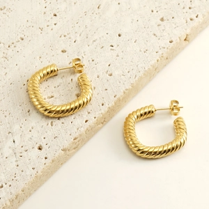 Détail de boucles d'oreilles créoles dorées torsadées avec texture en spirale