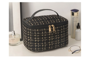 Detailed view of tyeed cosmetic bag with golden zippers and leather handle