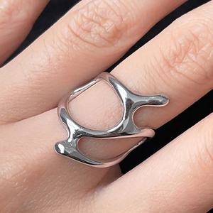 Macro view of a modern liquid-style irregular ring with a polished silver metallic finish