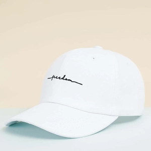 Detail shot of white baseball cap with black Freedom cursive embroidery and vent holes