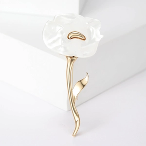 Macro view of matte white petals and gold stem detail of the elegant floral brooch