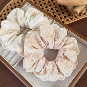 Detailed view of cream and pink lace scrunchies on a natural woven jewelry tray