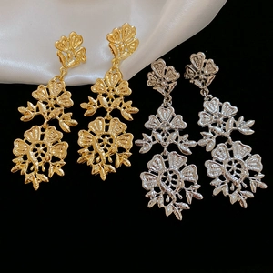 Detail view of gold and silver hollow flower drop earrings with baroque tassel design