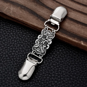 Close-up of vintage silver cardigan clip with floral engraving on leather background
