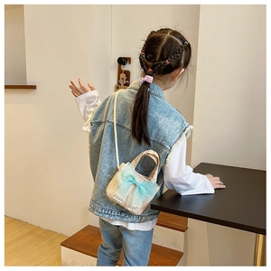 Girl wearing a handmade woven straw crossbody bag with light blue mesh bow and pearl detail