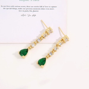 Elegant gold earrings with sparkling diamonds and large green teardrop crystals