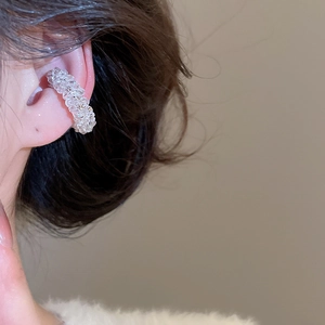 Detailed close-up of a French style beaded pearl ear cuff sparkling in warm soft lighting