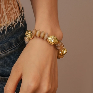 Detail of amber acrylic beads and irregular gold metal links on a female wrist