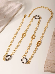 Macro detail of golden necklace featuring CD letter clasps and leopard pattern links